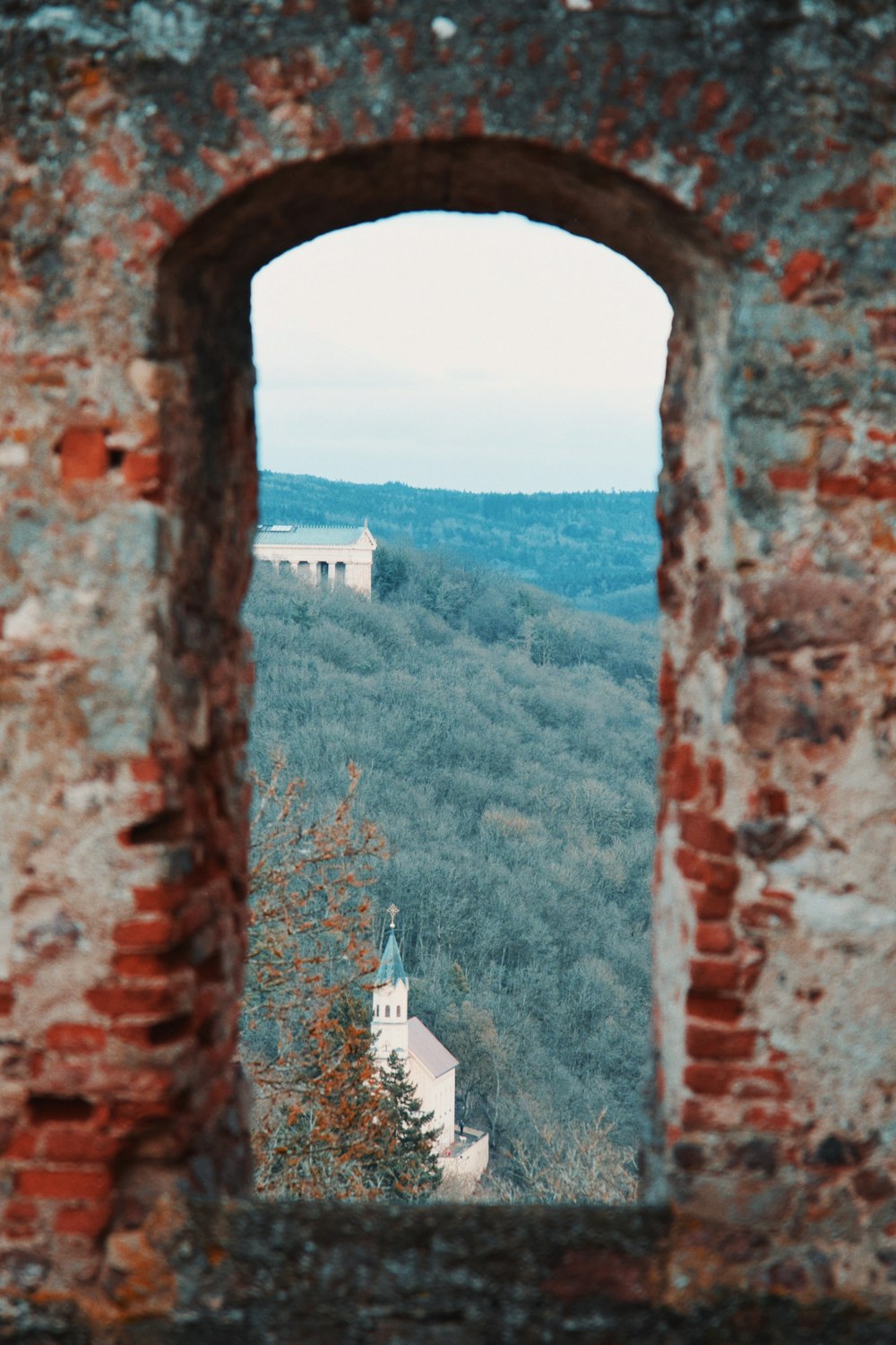 a window in an old brick wall with a view of the countryside