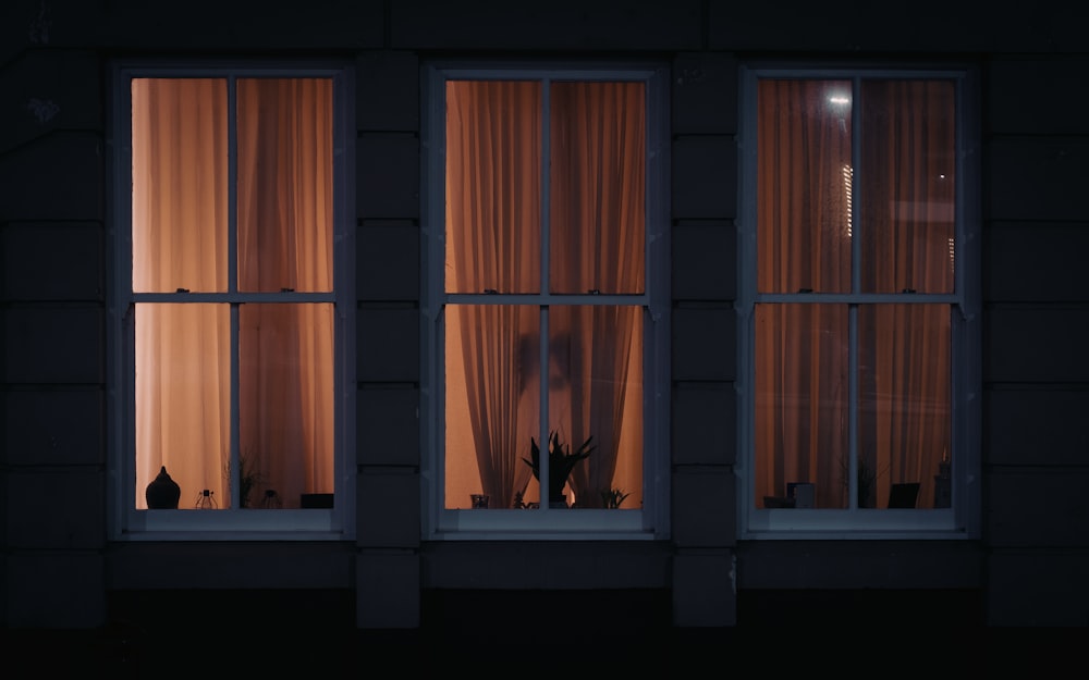 a dark room with three windows and curtains