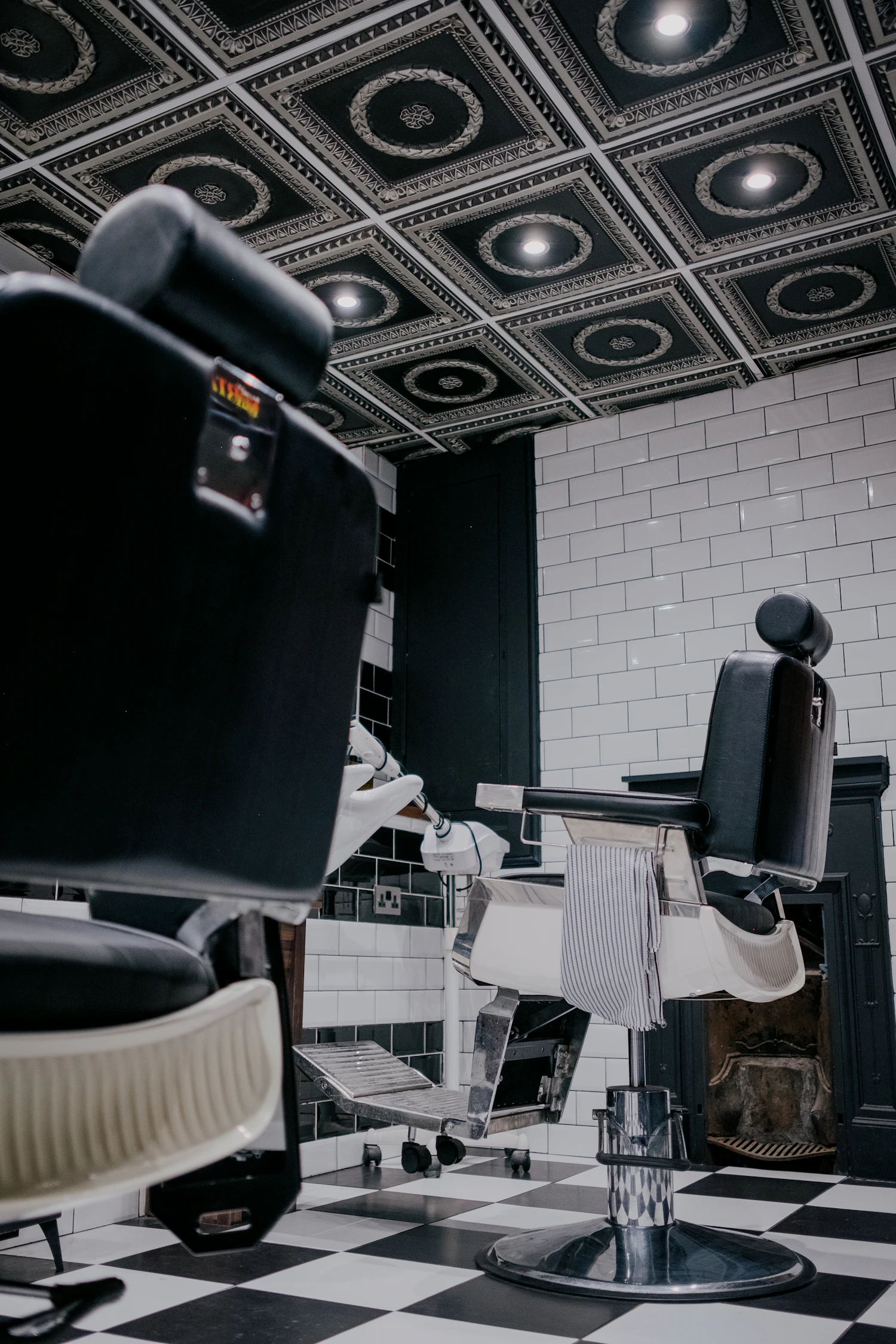 A barbershop with a black-and-white chequerboard floor and chairs along the wall