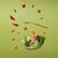 Floating food items including cherry tomatoes, almonds, cashews, slices of red bell pepper, cheese cubes, lettuce, and ham. A fork is levitating among these ingredients. The letters spelling 'DIET' are arranged with small tiles like a game. The background is a solid light green color.