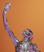A futuristic, metallic humanoid figure with a shiny, reflective surface, rendered in a skeletal form. It is posed with one arm raised, holding an apple-like object. The background is a solid orange, creating a contrast with the purple and silver tones of the figure.