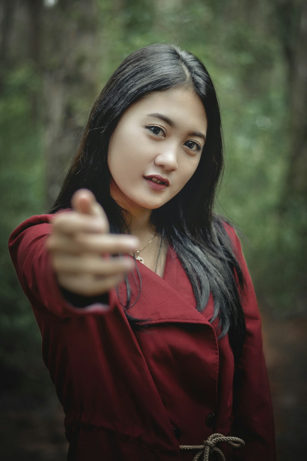 a woman in a red jacket pointing at the camera