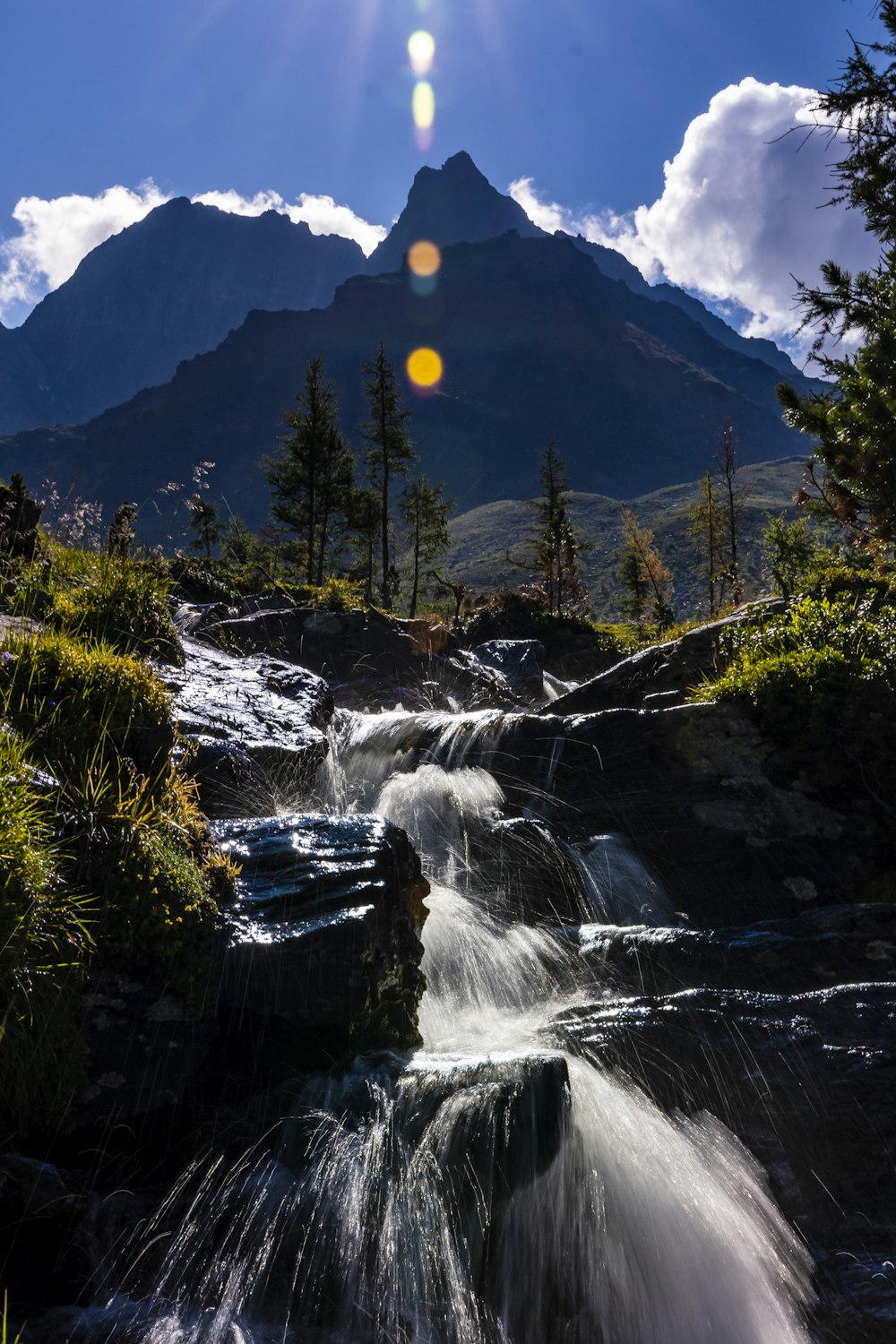 the sun shines brightly over a small waterfall