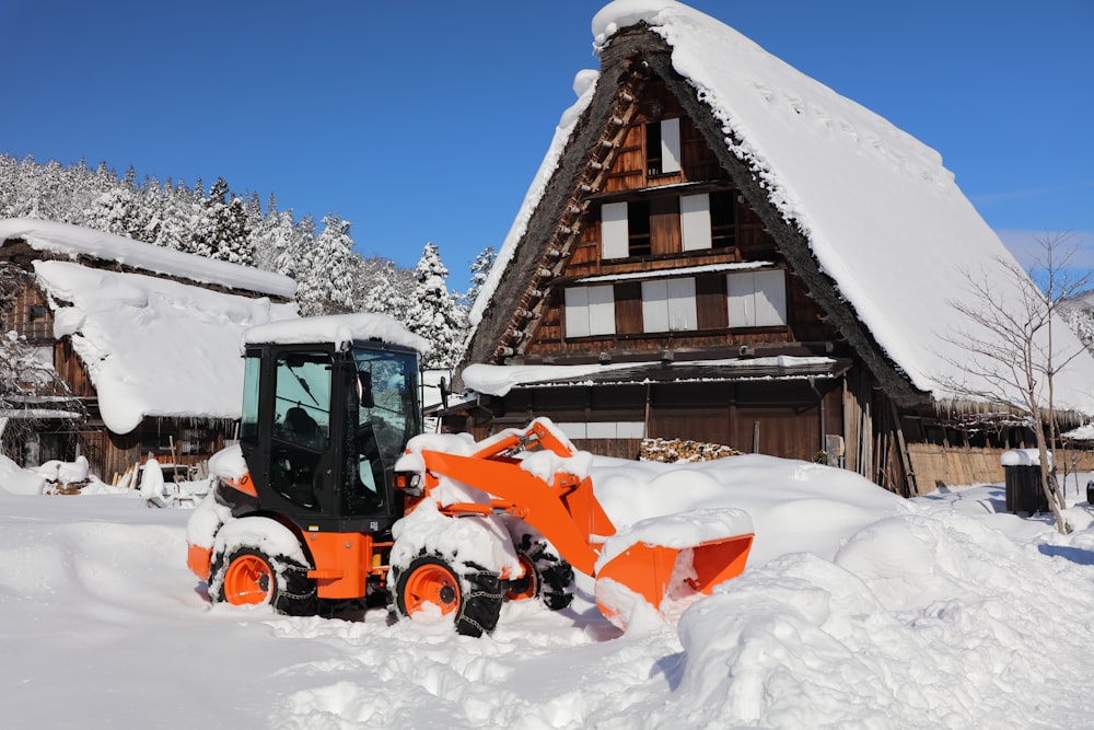 a tractor is parked in the snow in front of a house