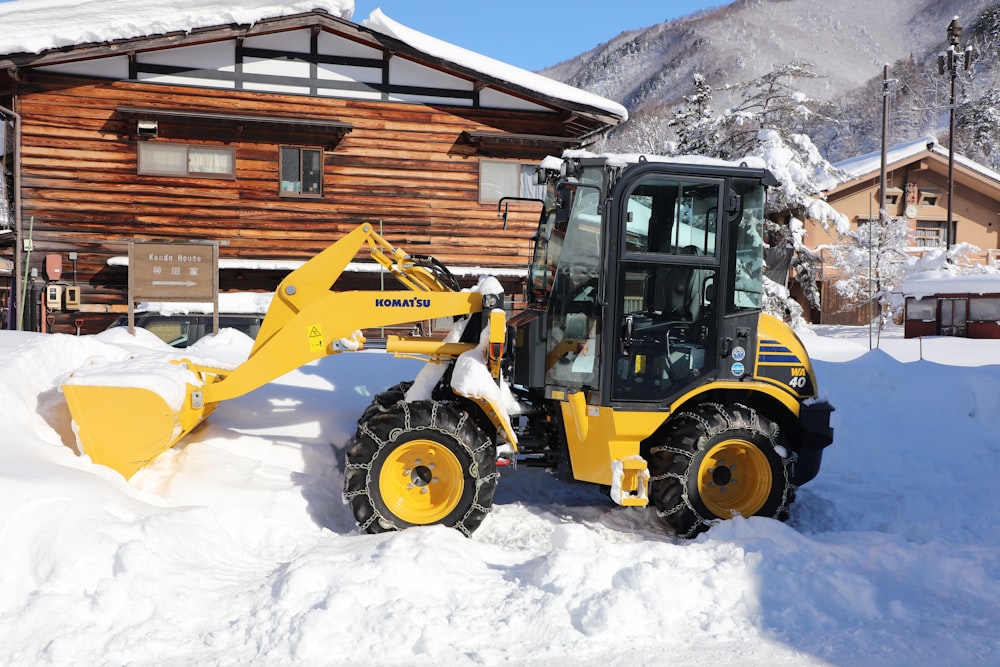 a tractor is parked in the snow in front of a house