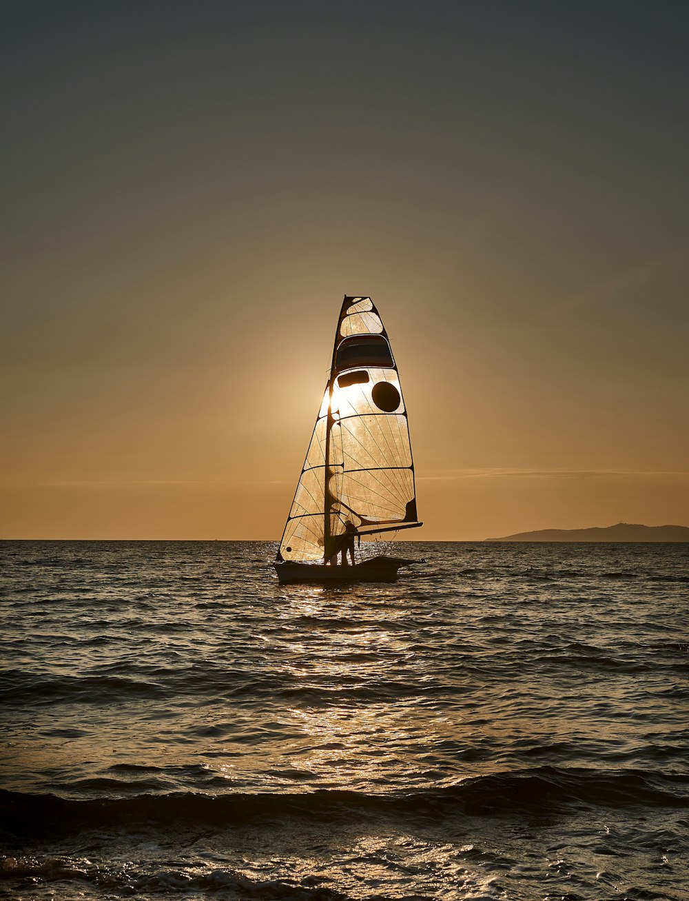 a sailboat sailing on the ocean at sunset