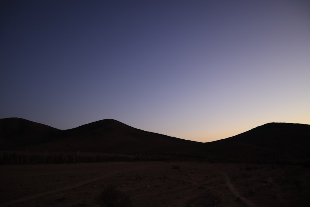 the sun is setting over the hills in the desert