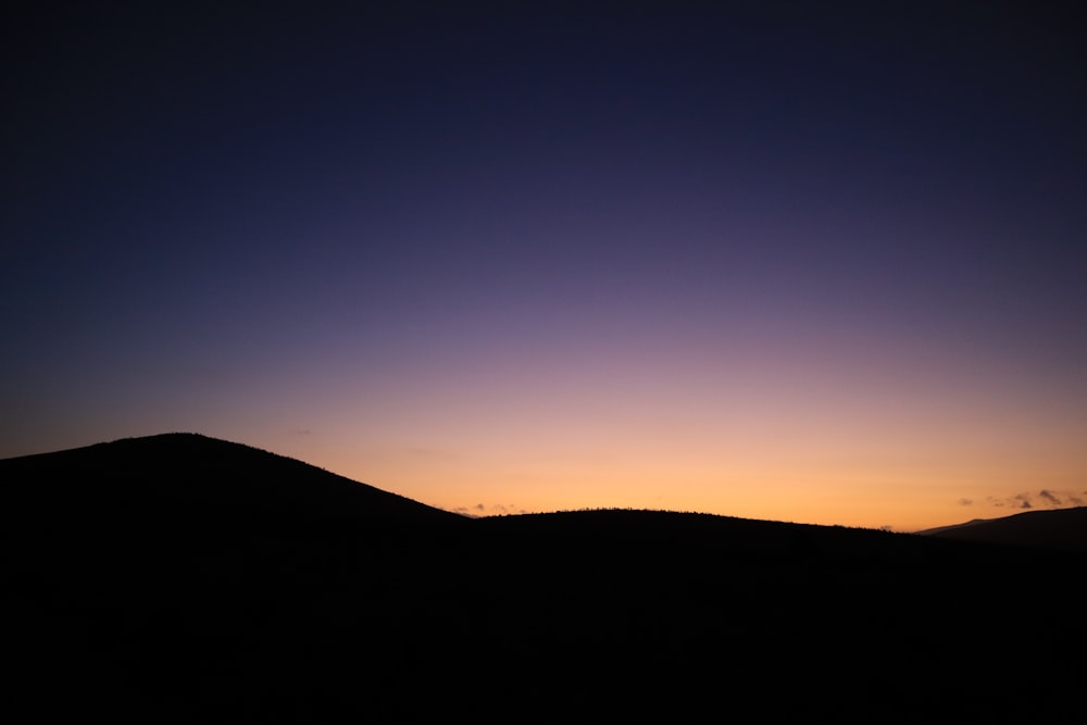 the sun is setting over a mountain range