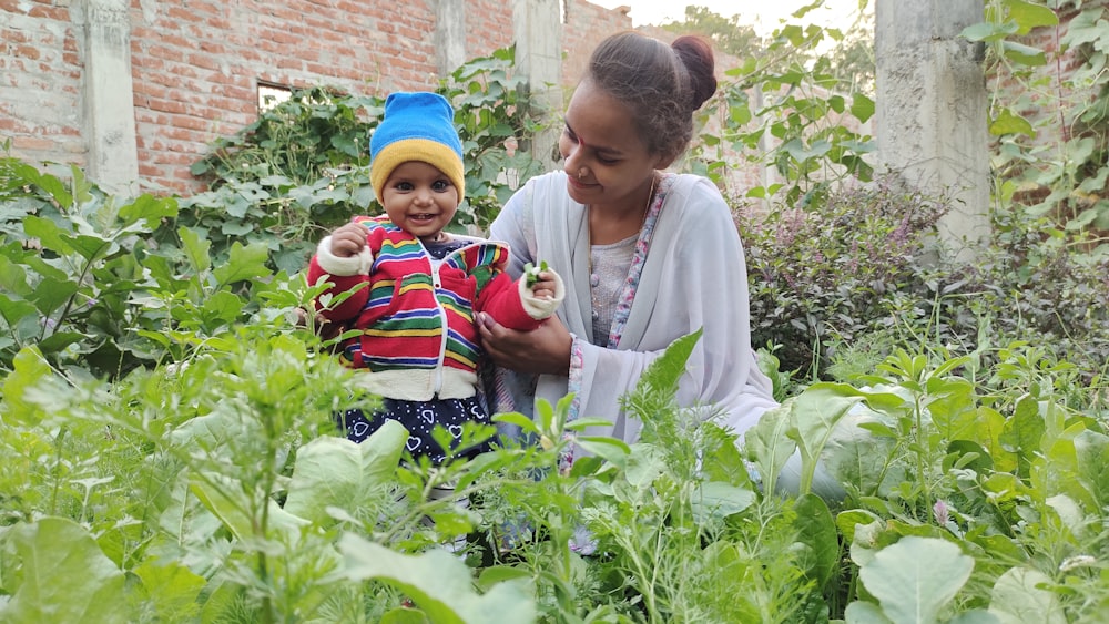 a woman holding a child in a garden