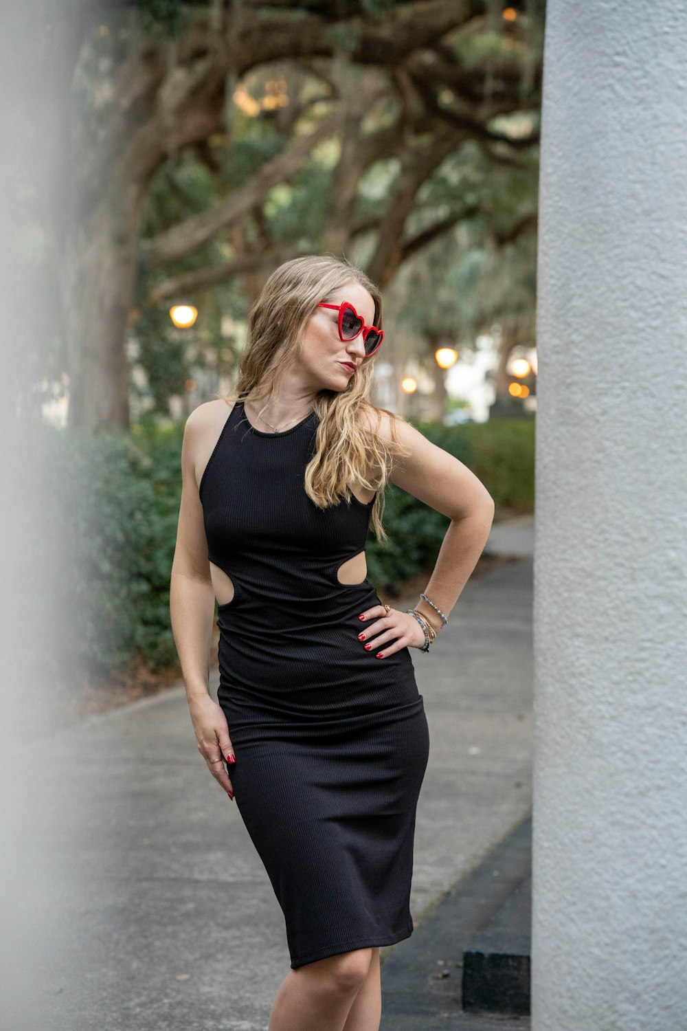 a woman in a black dress and red sunglasses