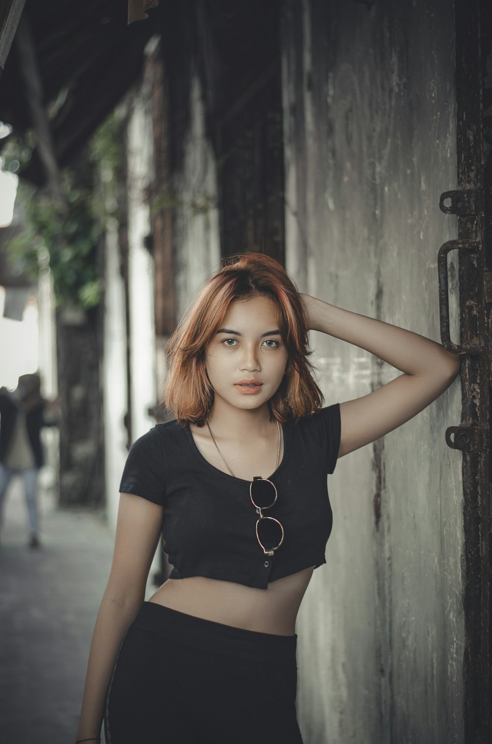 a woman standing next to a wall with her hand on her head