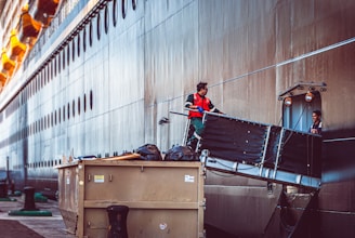 a man standing on top of a truck next to a large ship