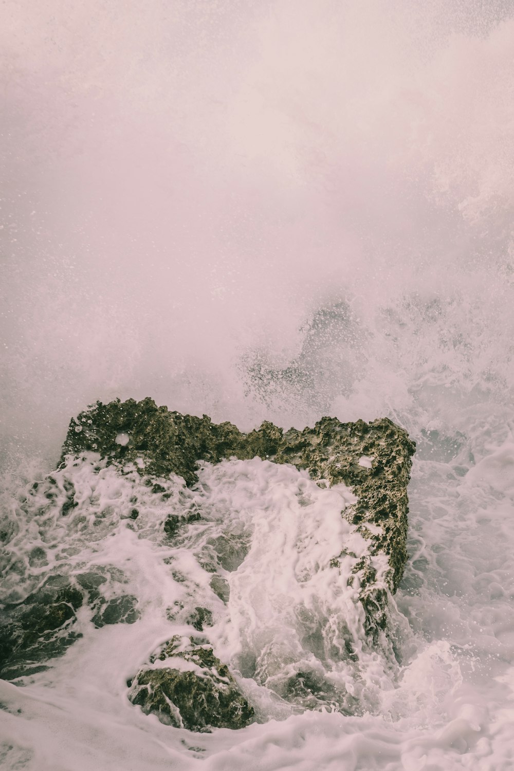 a person standing on a rock in the ocean