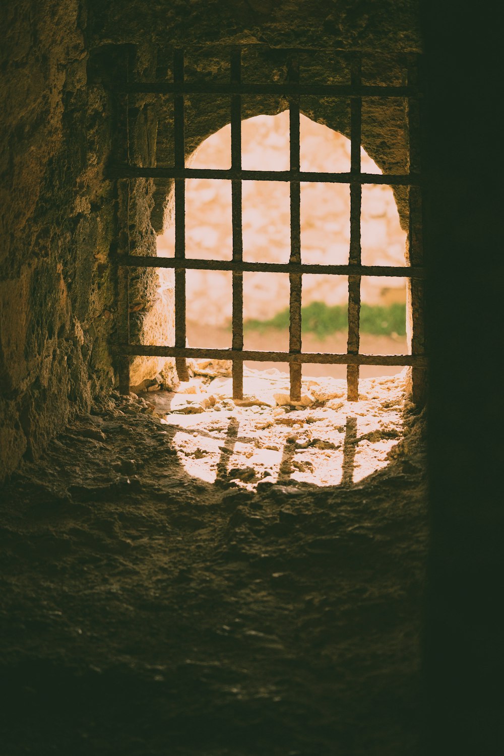 a window in a stone wall with bars on it