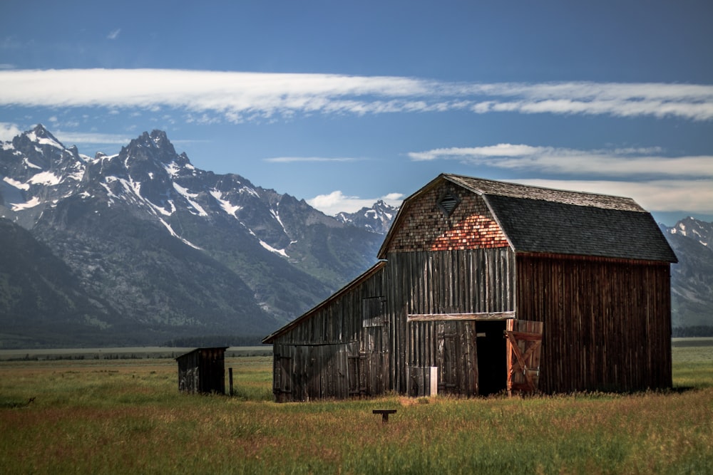 a barn in a field with mountains in the background