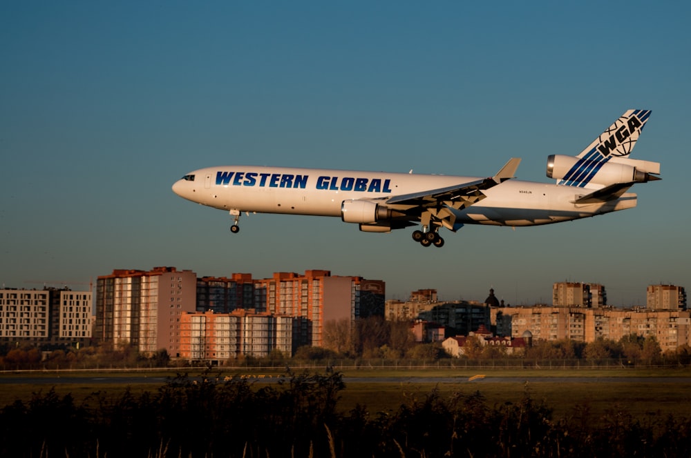 a large white airplane flying over a city