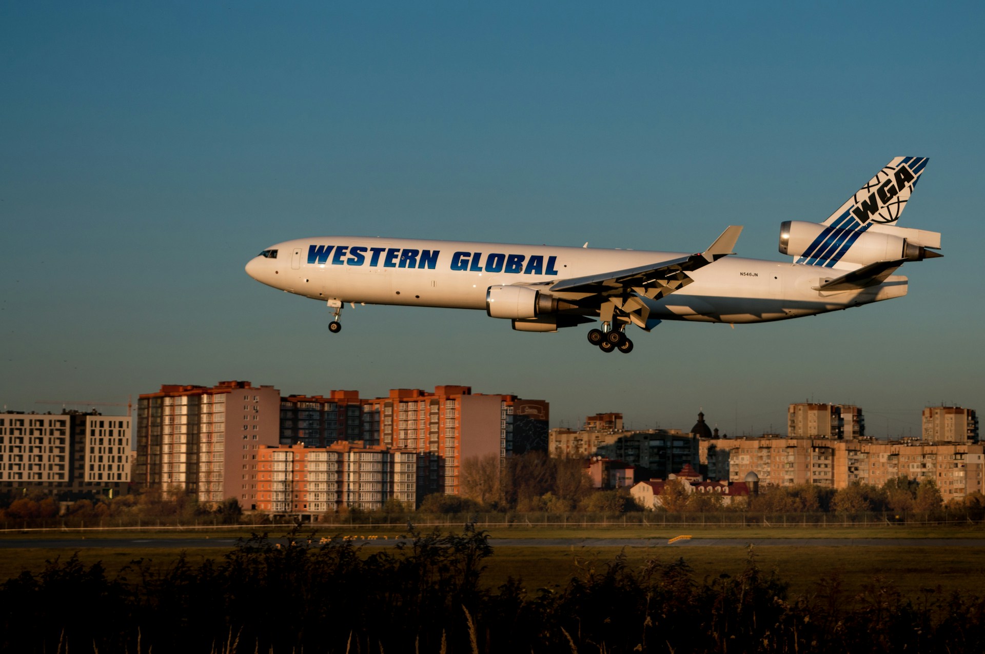 a large white airplane flying over a city