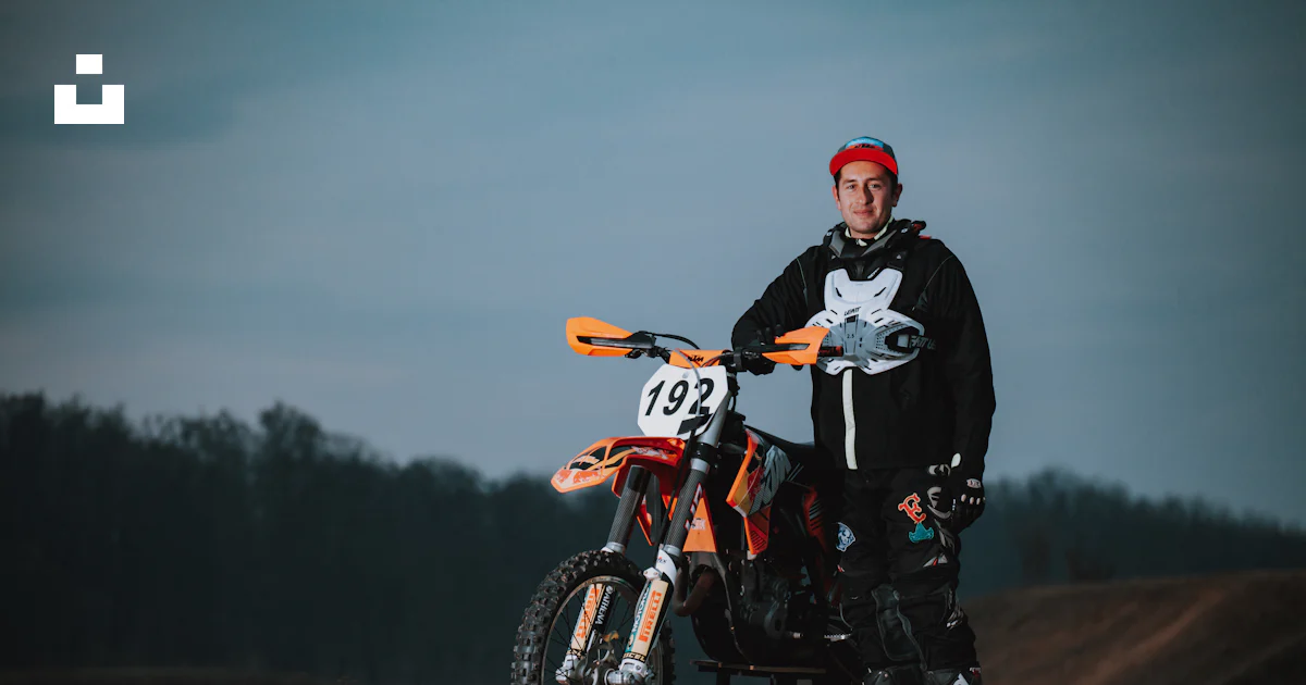 A man standing next to a dirt bike in a field photo – Free Motocross ...