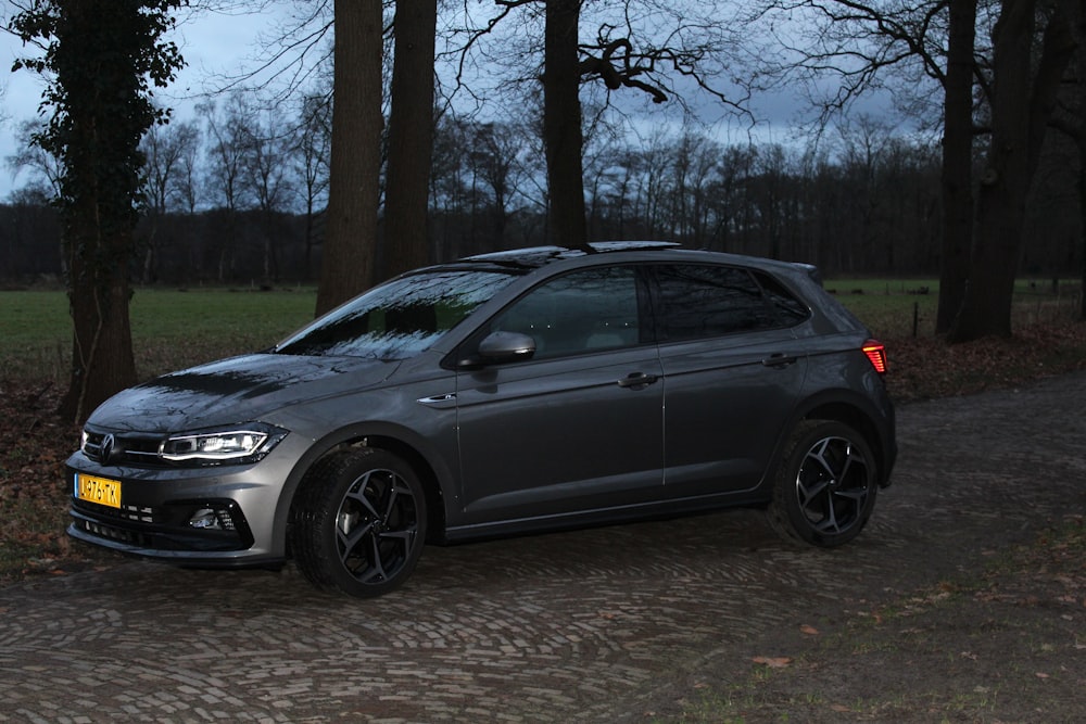 a grey car parked in front of some trees