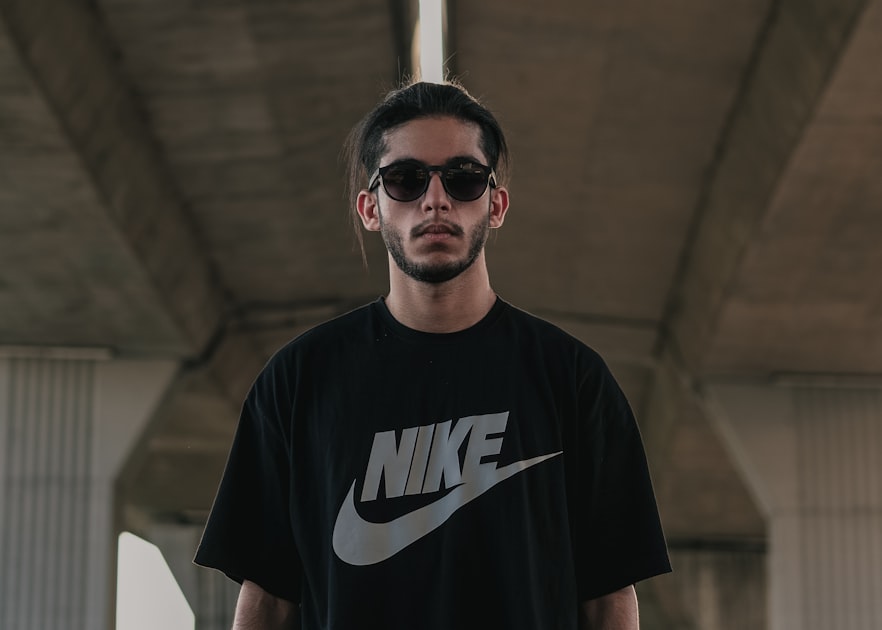 a man wearing a nike t - shirt and sunglasses