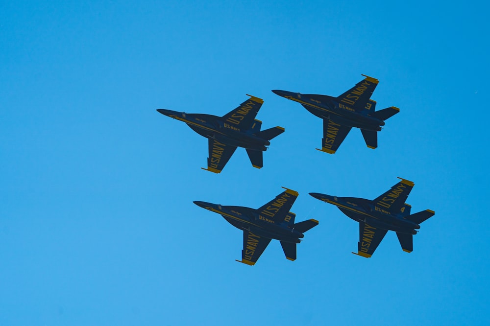 a group of four fighter jets flying through a blue sky