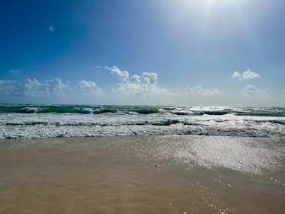 A pristine white sandy beach with gentle waves lapping under a clear blue sky.