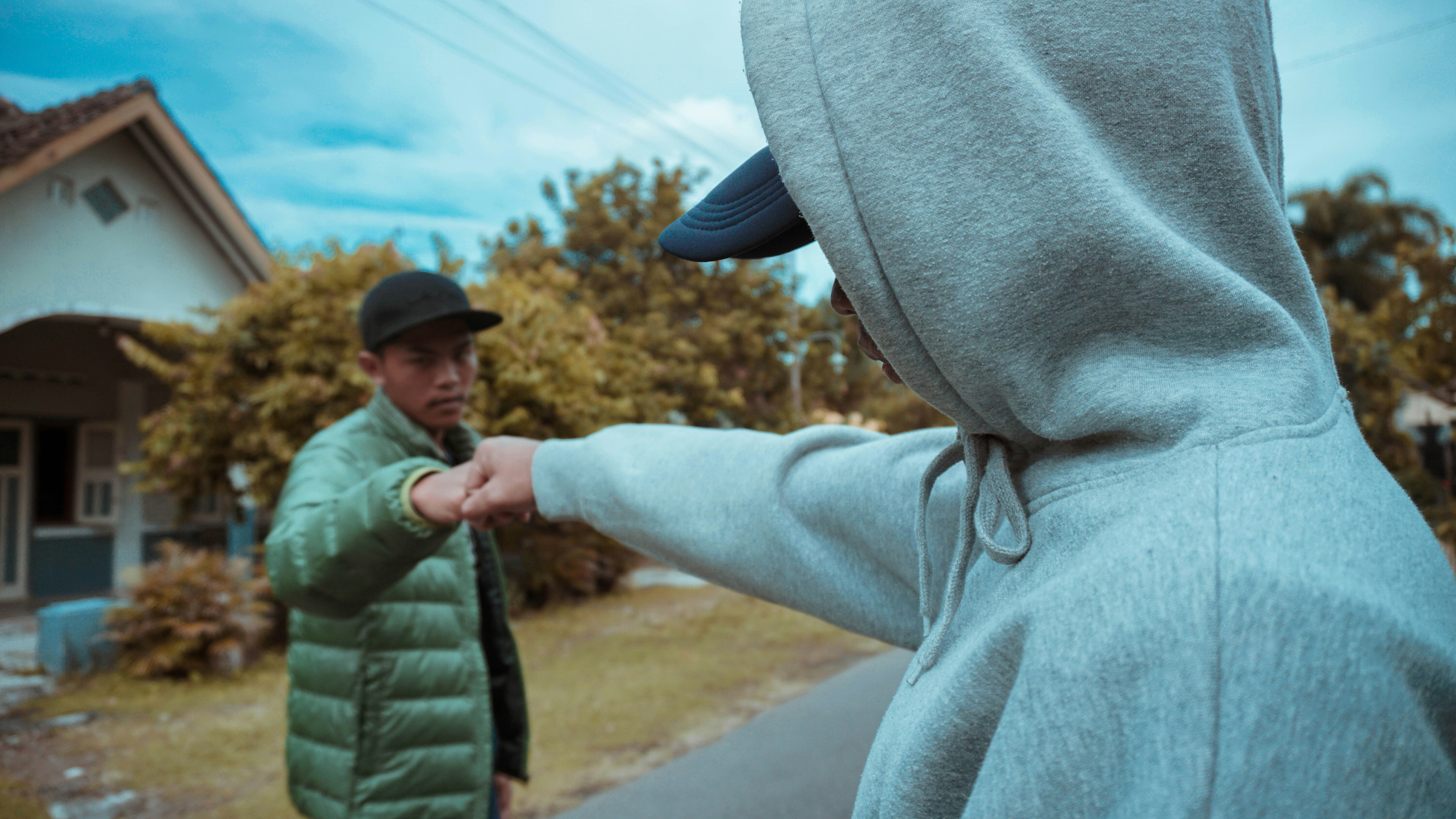 a man in a green jacket and a man in a black hat are facing each
