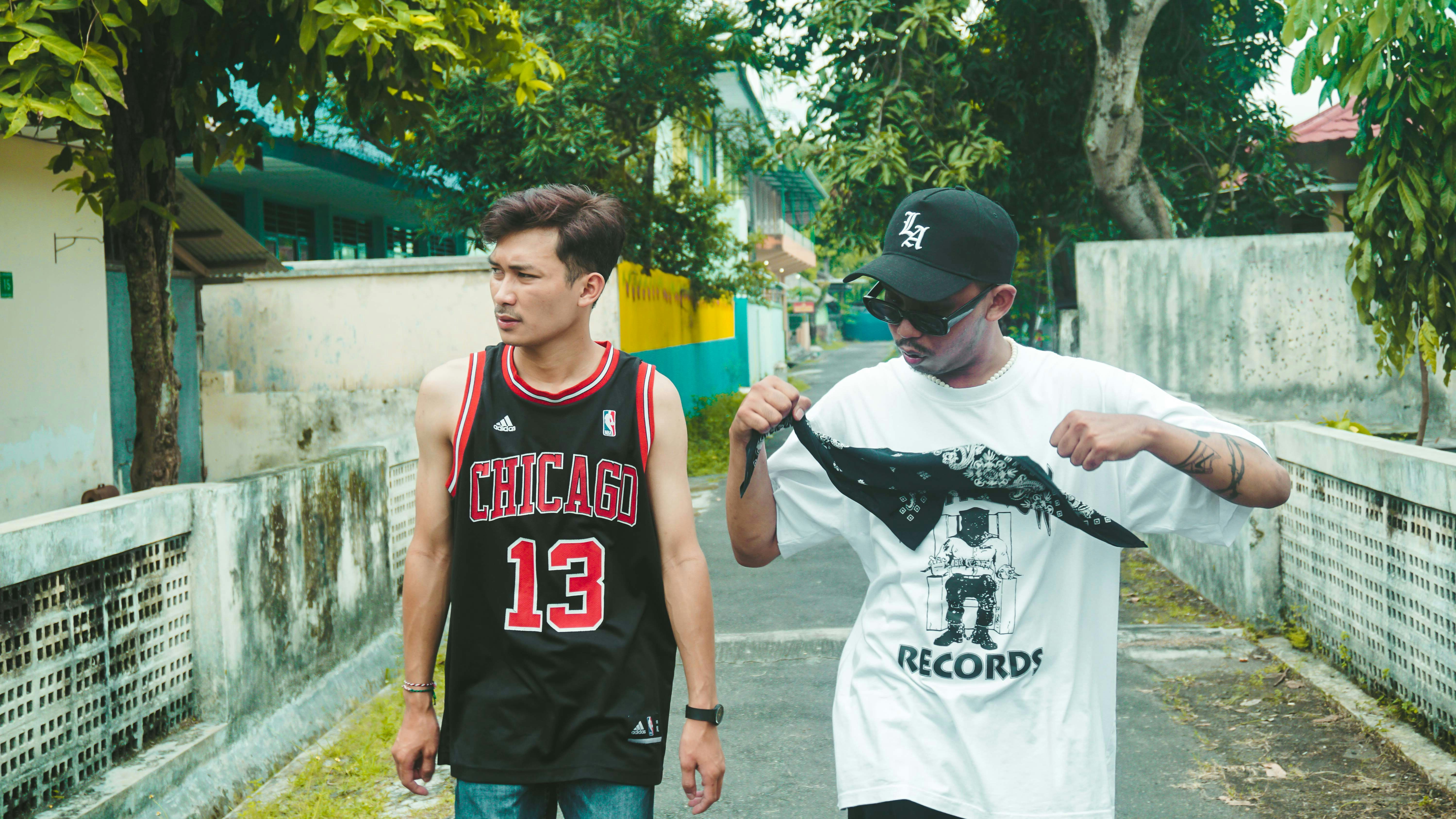 two young men standing next to each other on a street
