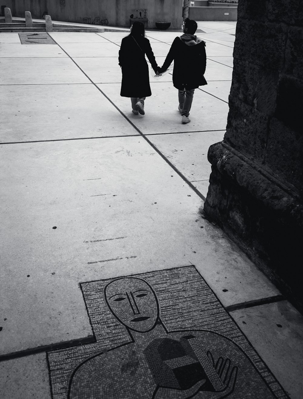 two people walking down a sidewalk holding hands