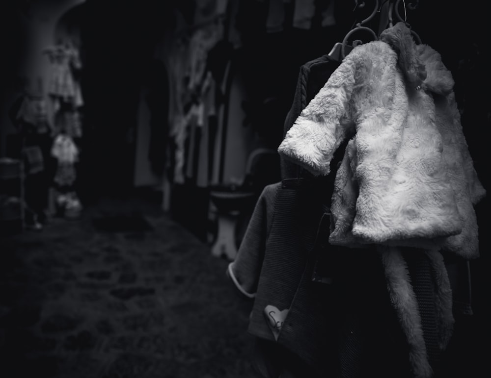Una foto in bianco e nero di un cappotto appeso a una linea di vestiti