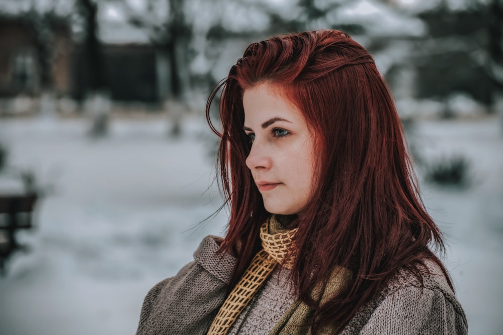 a woman with red hair is standing in the snow