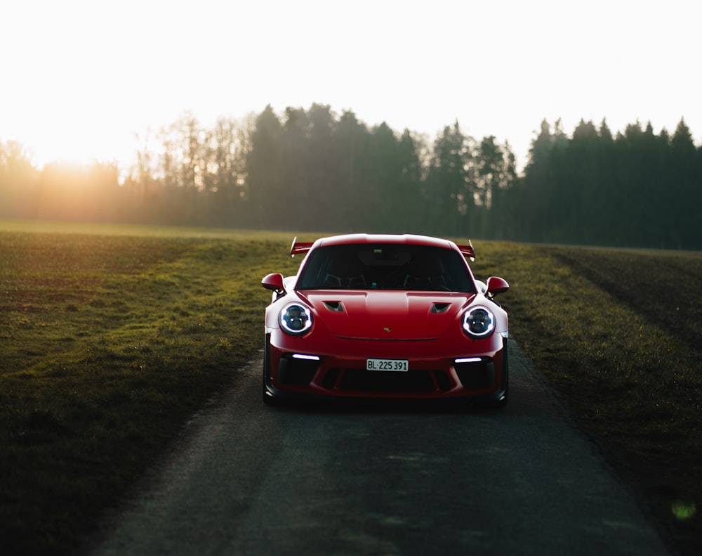 a red sports car driving down a country road
