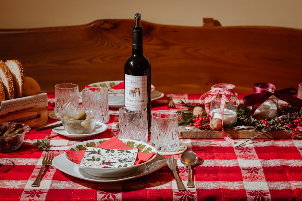 a table with a red and white checkered table cloth and a bottle of wine