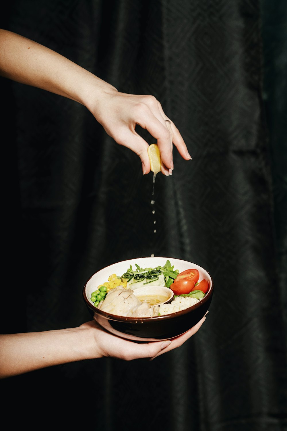 a woman is sprinkling dressing onto a bowl of food