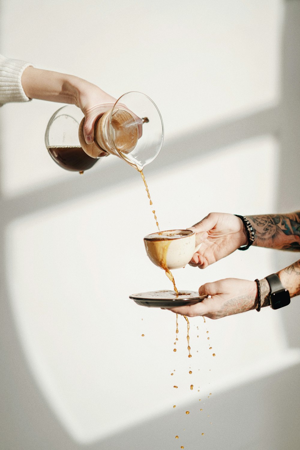 two people are pouring coffee into a cup
