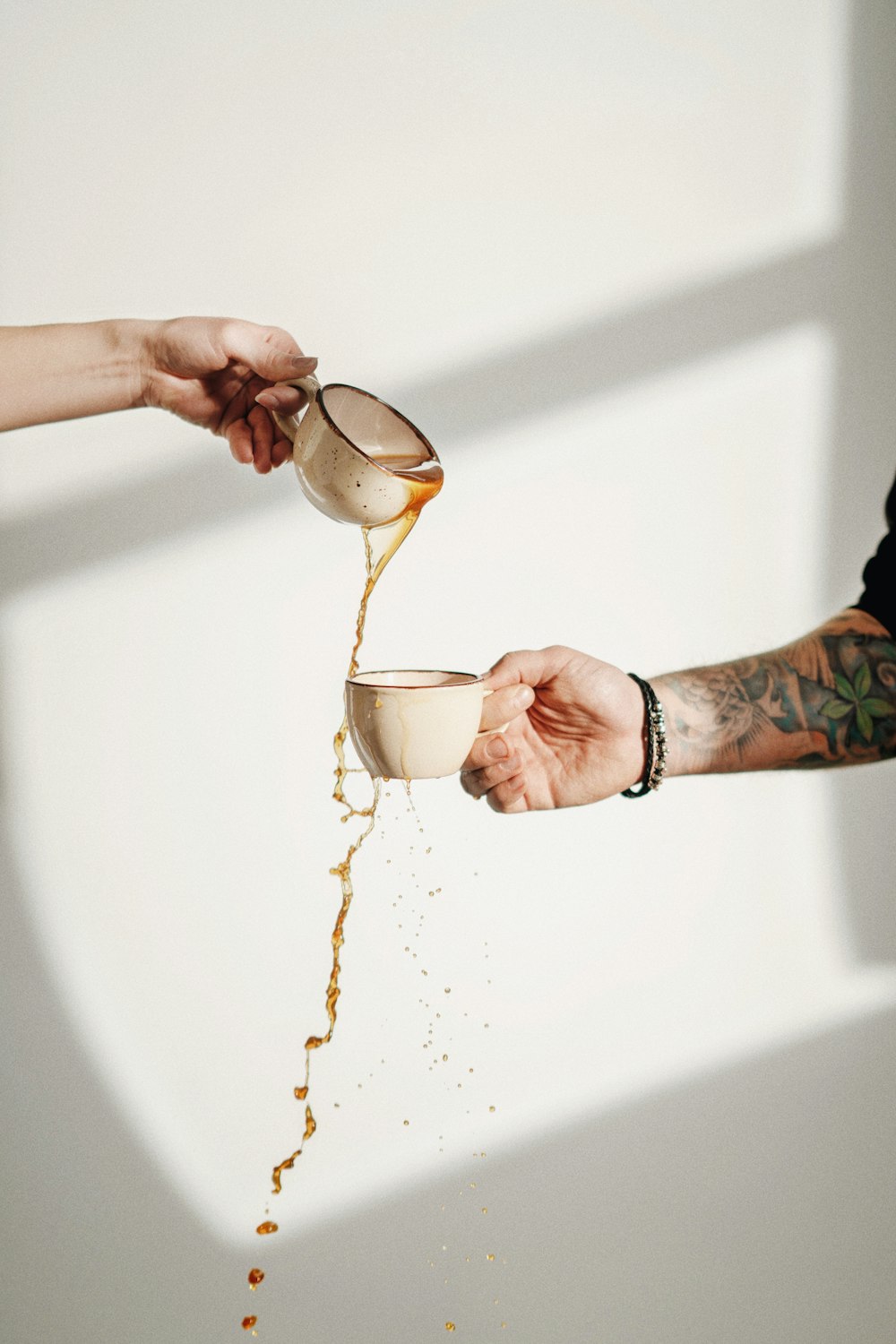 a person pouring a cup of coffee into another person's hand