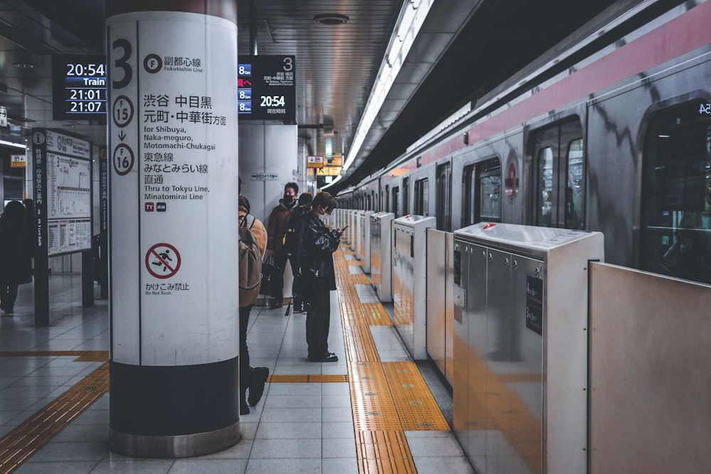 a group of people standing next to a train at a train station