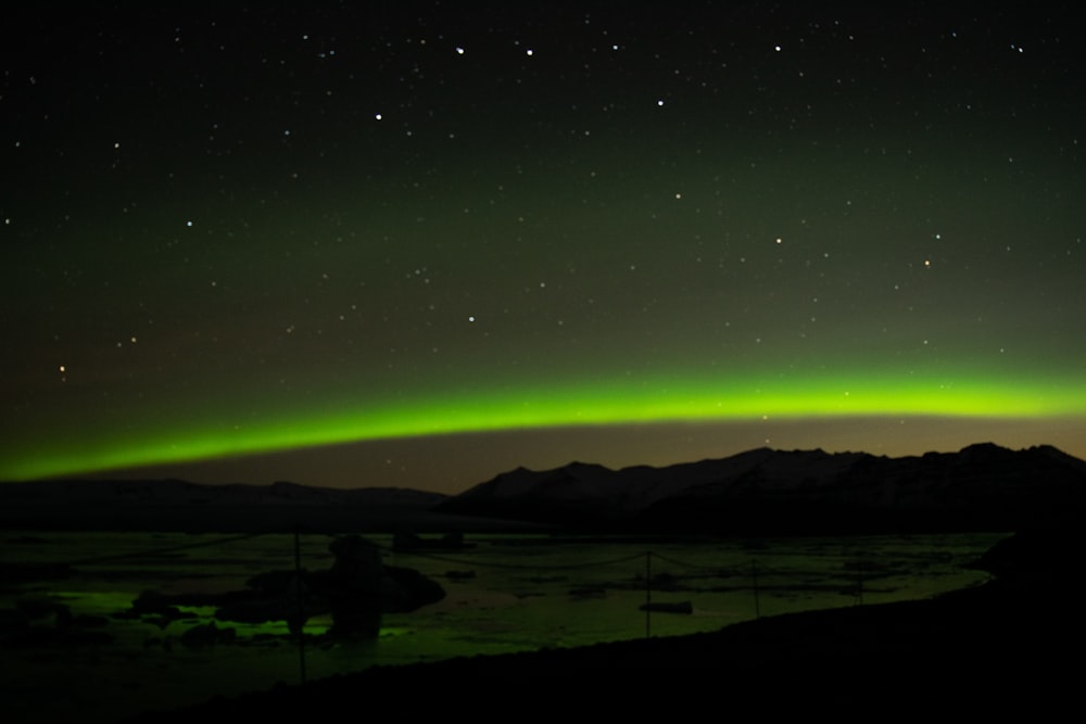 a green and black aurora over a mountain range