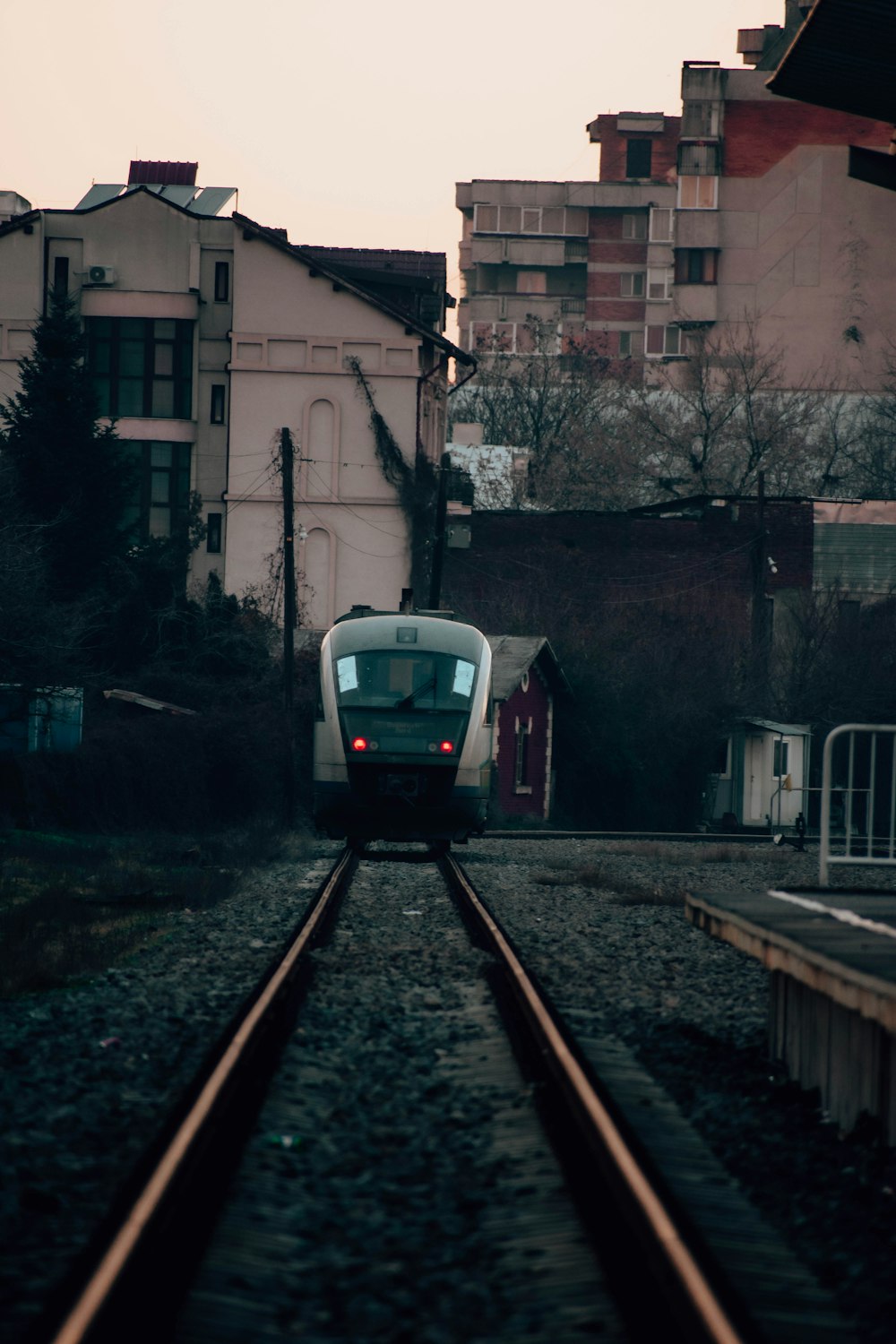 a train traveling down train tracks next to tall buildings