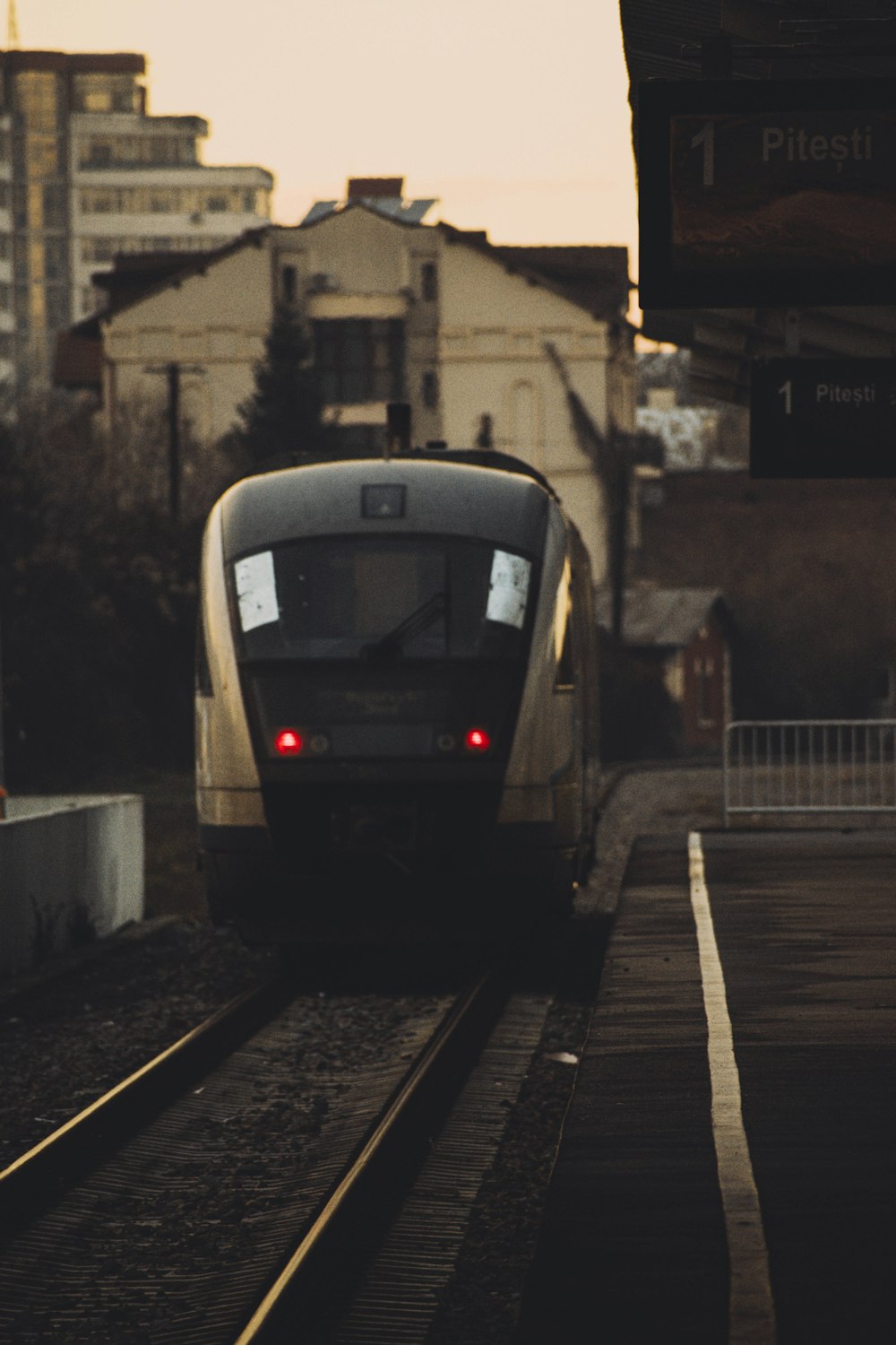 a train traveling down train tracks next to tall buildings