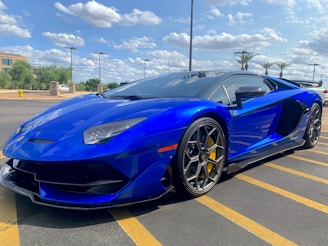 A sleek used car parked in front of the Al Najoom Auto Sales dealership under a clear blue sky.