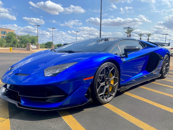 A sleek used car parked in front of the Al Najoom Auto Sales dealership under a clear blue sky.