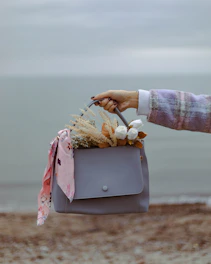 a woman holding a gray purse with flowers in it