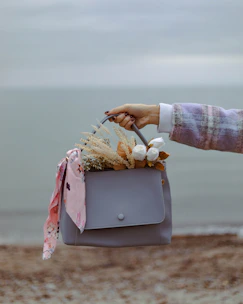 a woman holding a gray purse with flowers in it