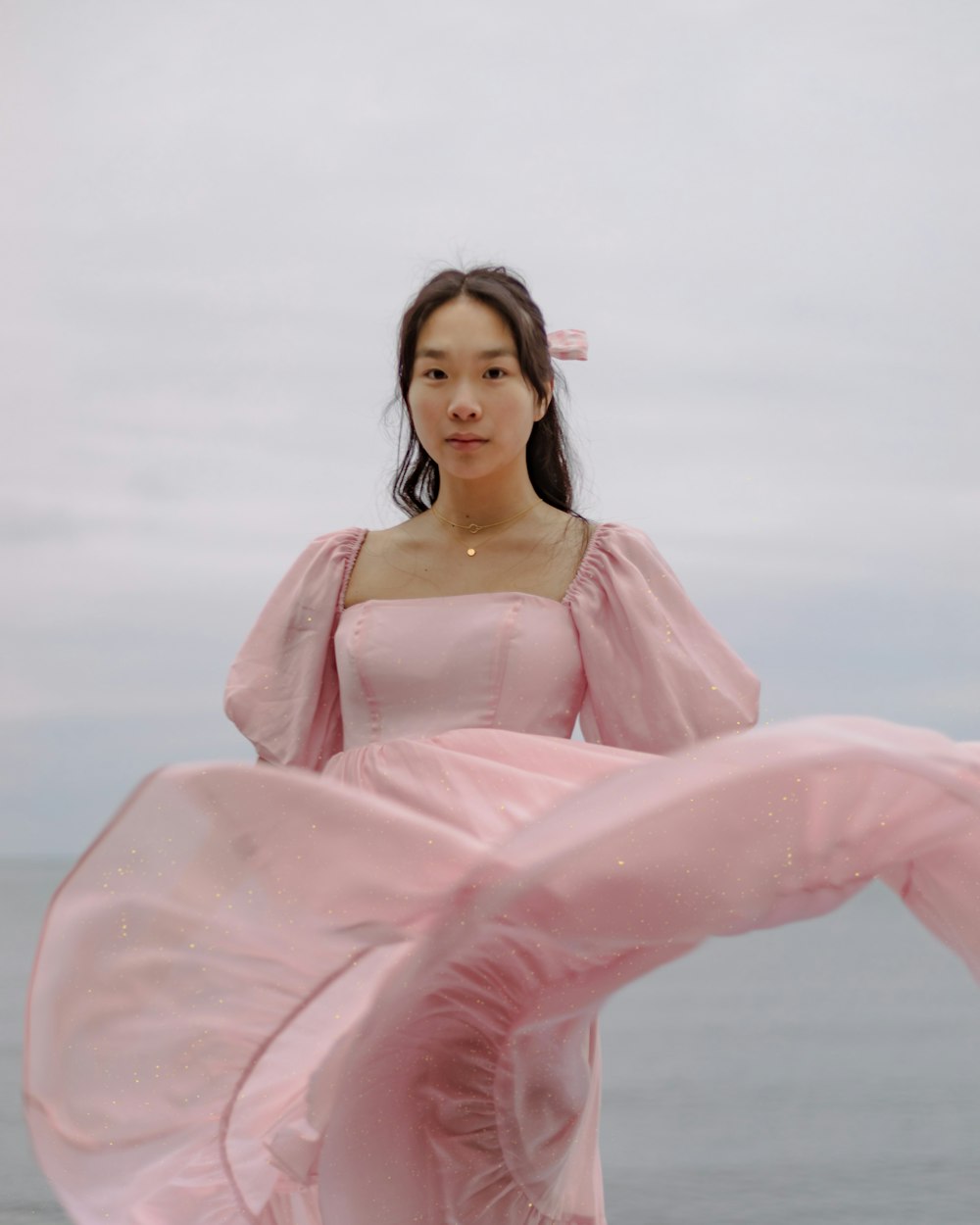 a woman in a pink dress standing on a beach