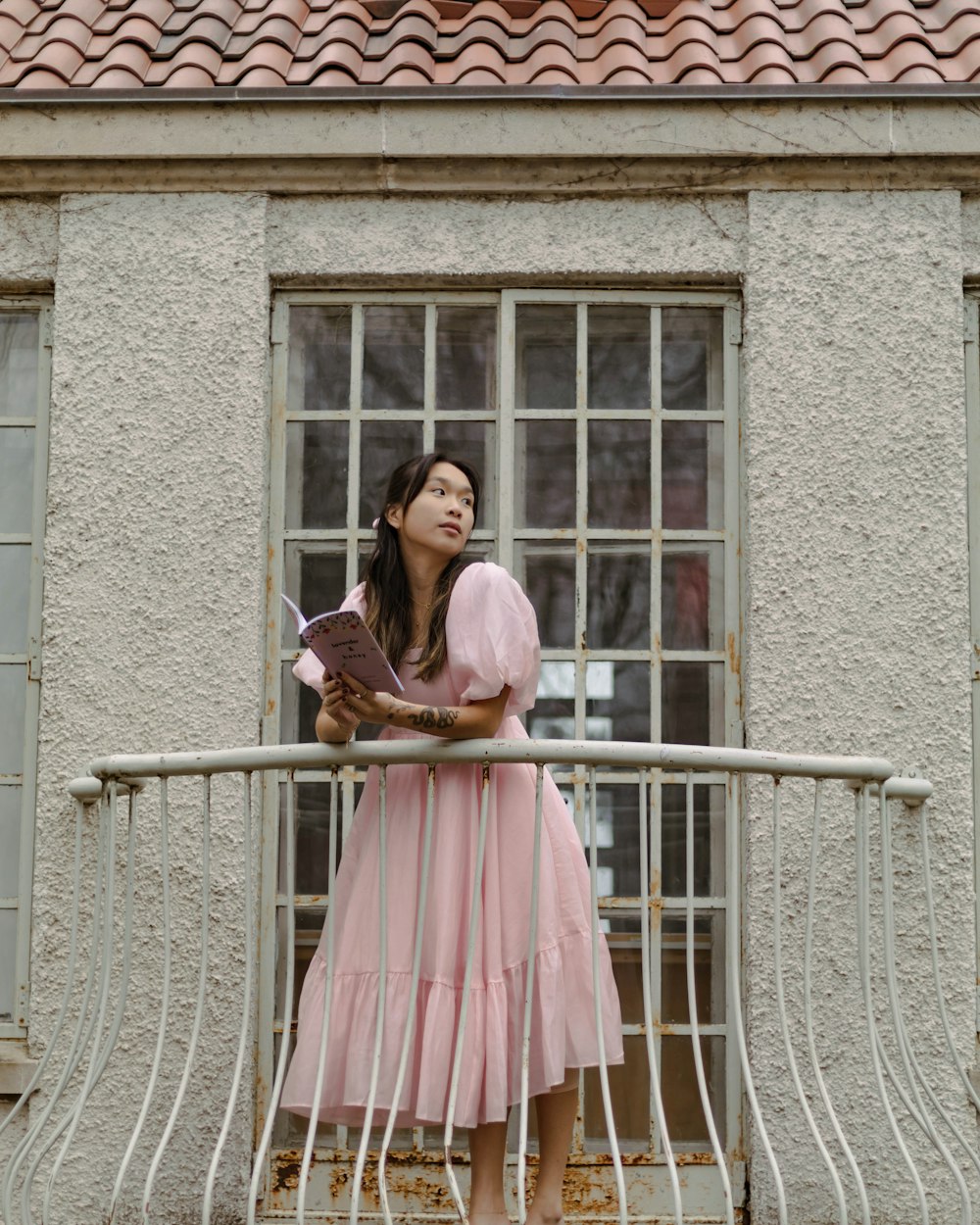 a woman in a pink dress standing on a balcony