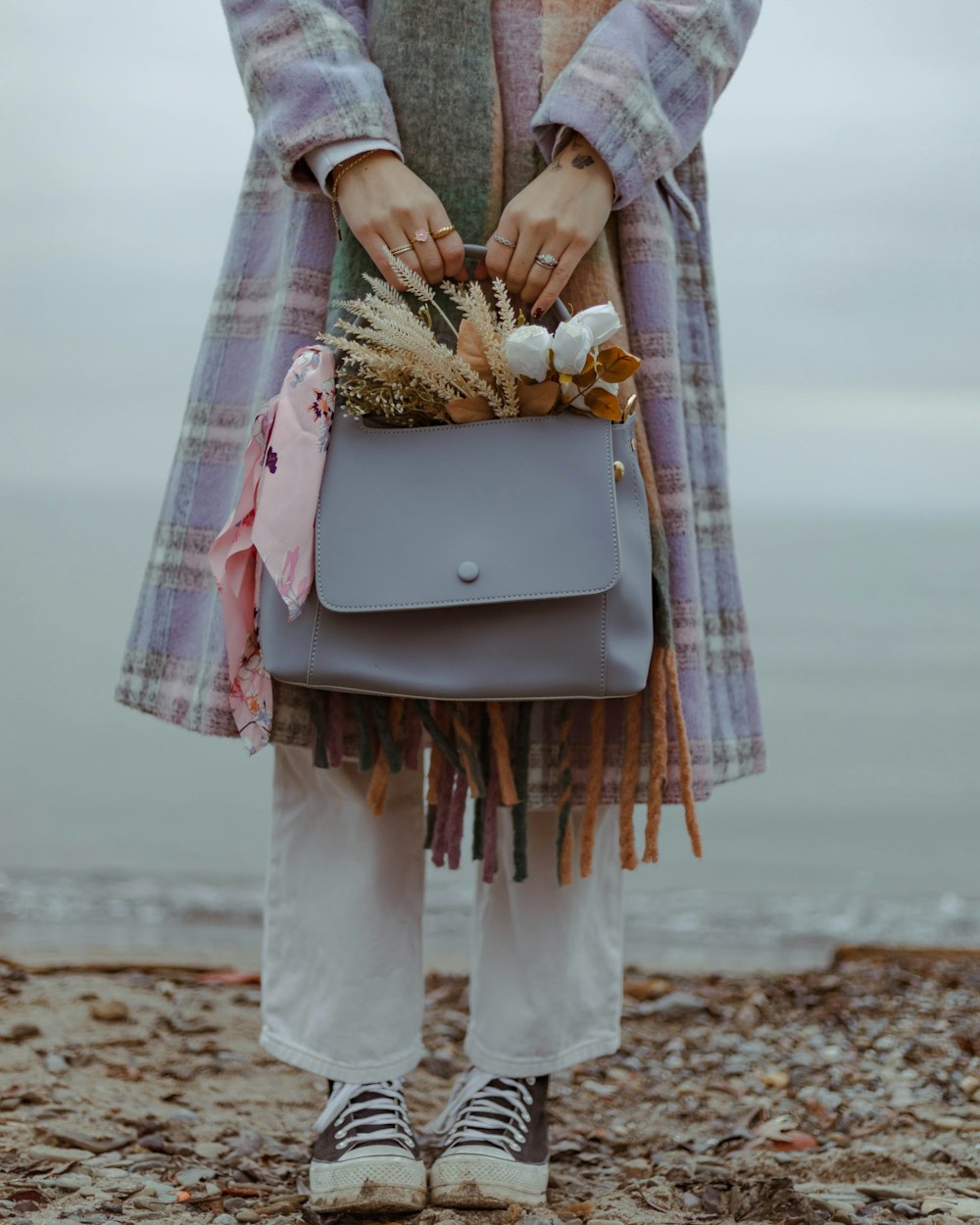 a woman holding a gray purse on a beach