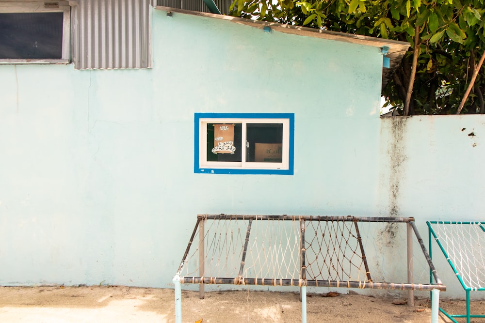 a blue building with a window and a bed