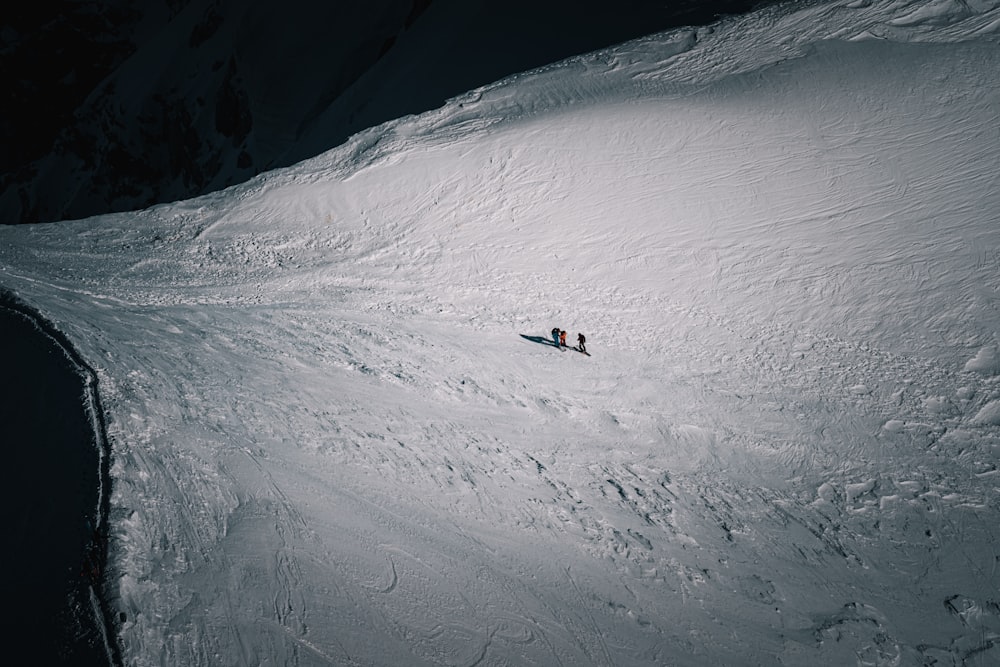 a couple of people riding skis down a snow covered slope