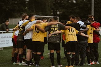 a group of soccer players huddle together on the field